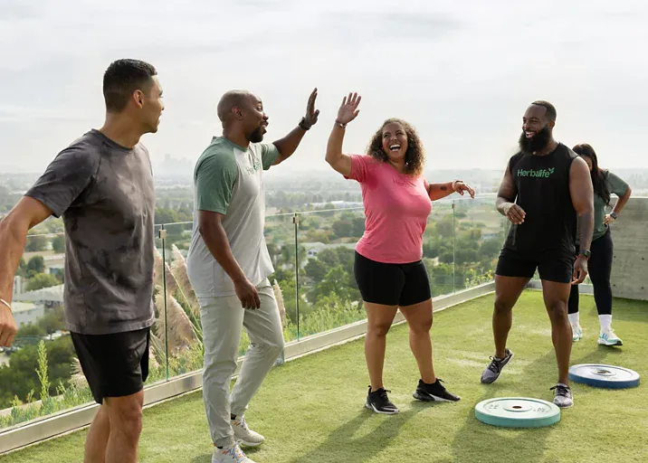 Grupo ejercitándose al aire libre, sonriendo y chocando las manos